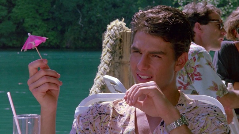 Brian Flanagan holding a cocktail umbrella next to a lake in Cocktail