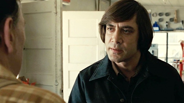 Javier Bardem as Anton Chigurh, grimacing at a store clerk in No Country for Old Men