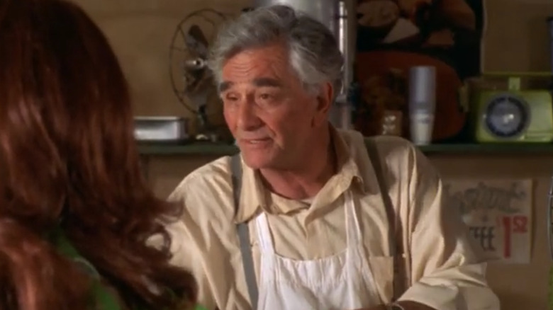 Peter Falk as Abel Shaddick standing behind the meat counter talking to a customer in A Storm In Summer