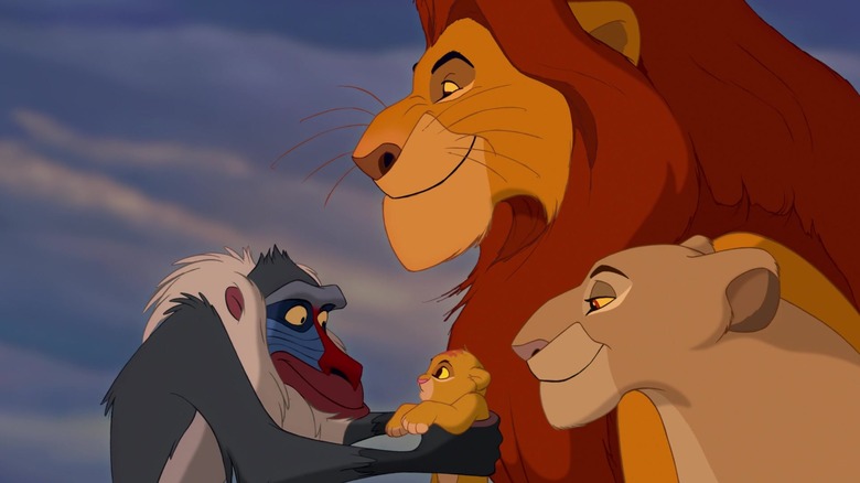 Rafiki holding Simba while his mom and dad look on in The Lion King