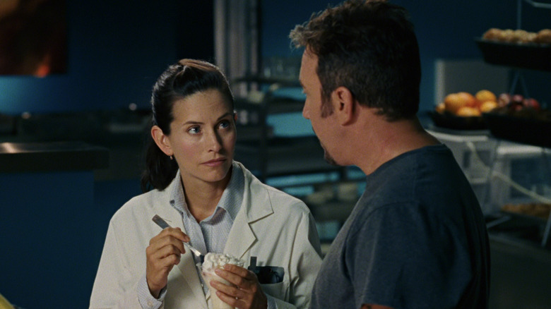 Courteney Cox's Dr Marsha Holloway looks up at Tim Allen's Jack Shepard/Captain Zoom as she eats a yogurt in Zoom