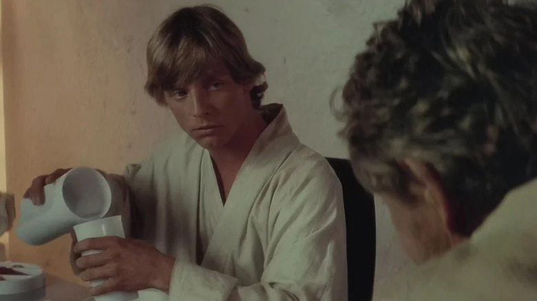 Luke Skywalker derramando um copo de leite azul enquanto ele olha para seu tio Owen em uma mesa de jantar em Star Wars: uma nova esperança
