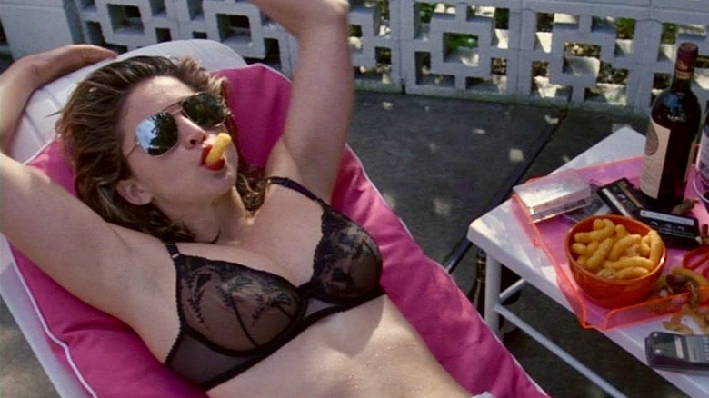 Madonna as Susan Thomas sports a black bra and mirrored sunglasses as she sucks on a cheese puff in Desperately Seeking Susan
