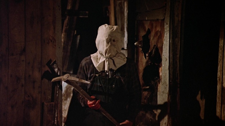 Jason Voorhees standing in his shack with a pickaxe in Friday the 13th Part 2