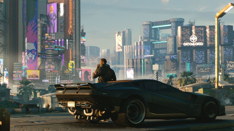 Gavin Drea as the voice of V leaning against his car on a road overlooking Night City in Cyberpunk 2077