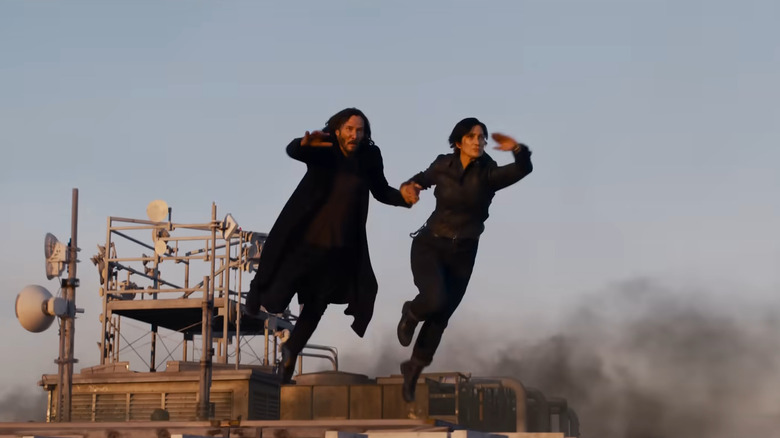 Keanu Reeves and Carrie-Anne Moss jumping through the air