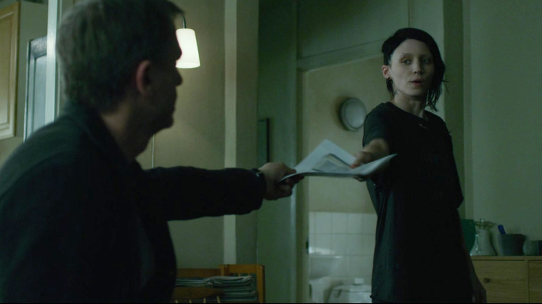 Daniel Craig's Mikael Blomkvist hands papers to Rooney Mara's Lisbeth Salander in The Girl with the Dragon Tattoo
