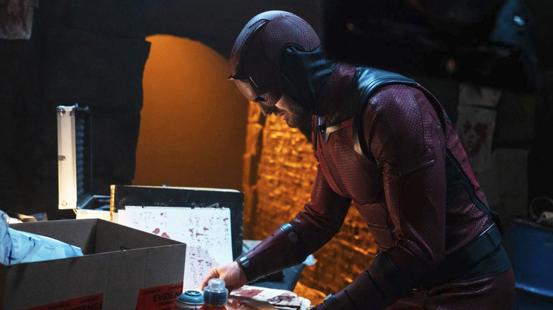 Charlie Cox's Matt Murdock searching through some papers in his Daredevil suit in Daredevil: Born Again