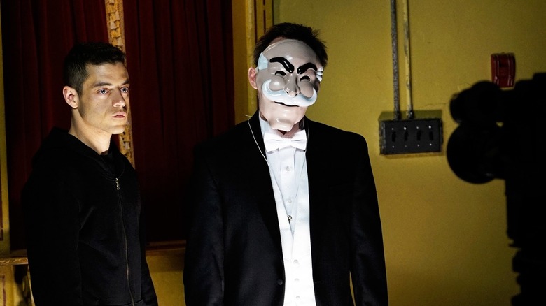 Rami Malek as Elliot Alderson standing next to Christian Slater as Mr. Robot wearing a mask in Mr. Robot
