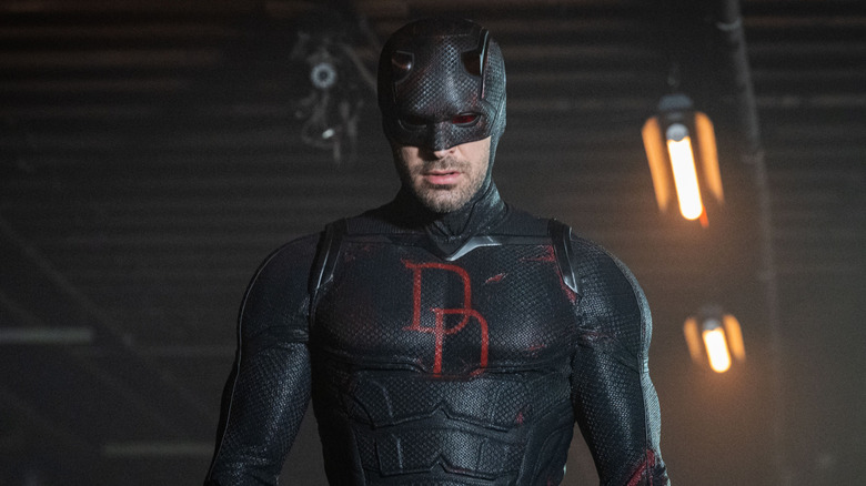 Charlie Cox suited up as Daredevil in his black suit walking through a warehouse in Daredevil: Born Again