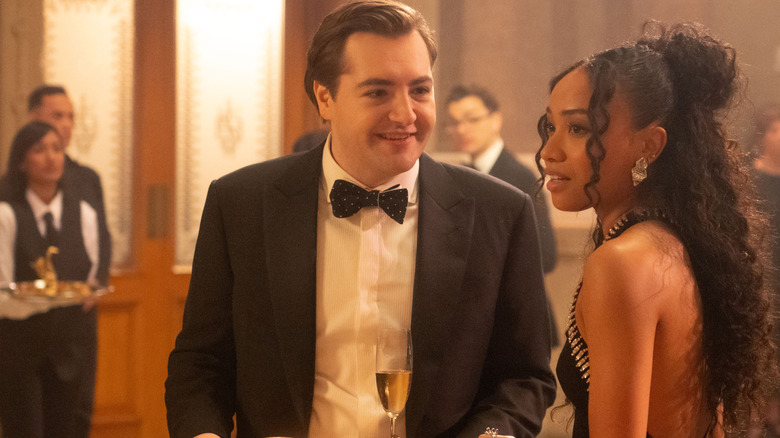 Michael Gandolfini as Daniel Blake wearing a tuxedo at a cocktail party next to Genneya Walton as BB Urich in Daredevil: Born Again