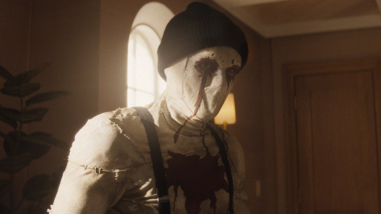 Hunter Doohan as Muse wearing a creepy mask and ski cap in an office in Daredevil: Born Again Season 1