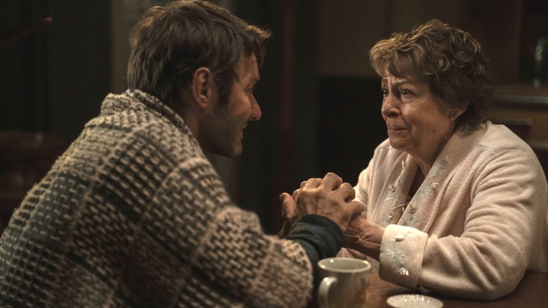 Joel Edgerton as Jason Dessen holding hands with Linda Bove as Ellie Dessen while seated at a coffee table in Dark Matter