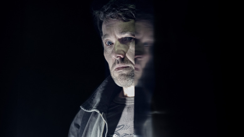 Joel Edgerton as Jason Dessen standing next to a black reflective surface in Dark Matter