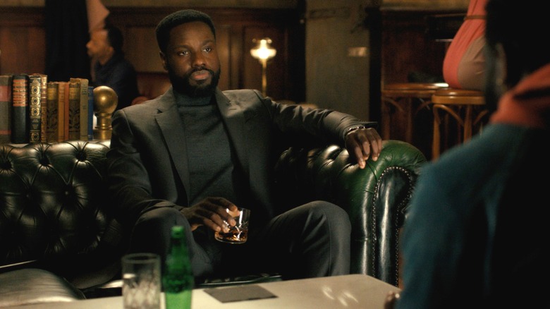 Dayo Okeniyi as Leighton Vance wearing a suit and sitting on a sofa opposite another version of himself in Dark Matter