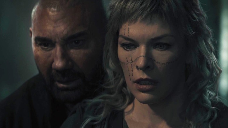 Dave Bautista as Boyce standing behind Milla Jovovich as Gray in In the Lost Lands