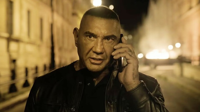 John Flood (Dave Bautista) holding a phone to his ear in 