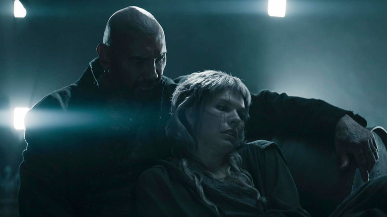 Dave Bautista as Boyce and Milla Jovovich as Gray Alys sit together in In the Lost Lands