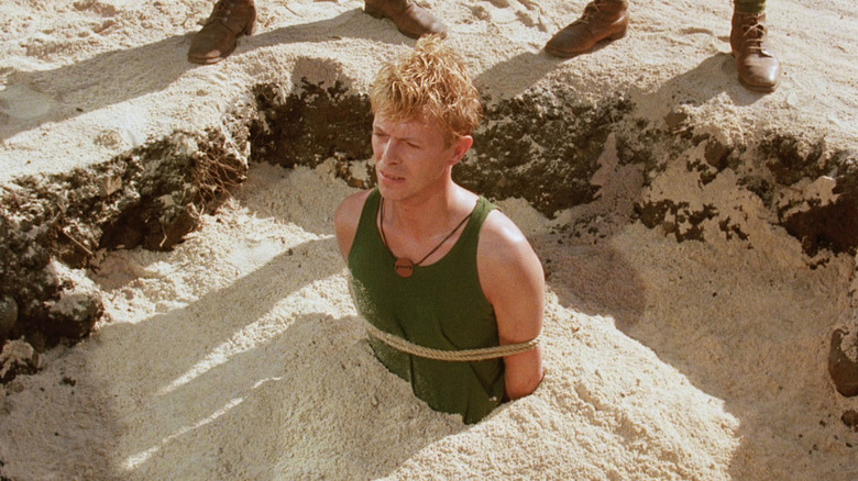 David Bowie's Maj. Jack "Strafer" Celliers is seen with his hands tied while half buried in sand in Merry Christmas, Mr. Lawrence.jpg
