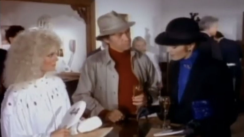 David Carradine's Hermanski stands between Lynda Carter's Carole Stanwyck and Loni Anderson's Sydney Kovack at an auction in Partners in Crime