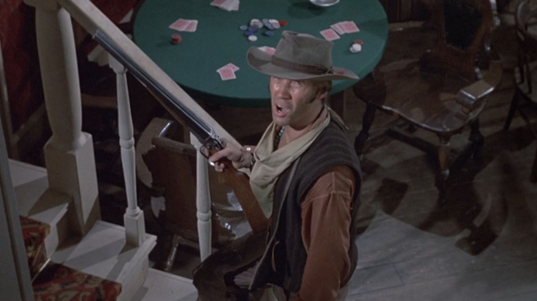 David Carradine's Jesse Boone stands holding a rifle on saloon staris in Young Billy Young