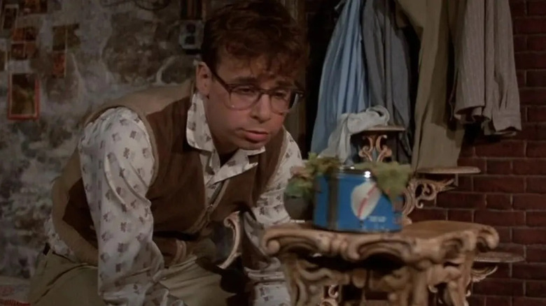 Seymour Krelborn (Rick Moranis) monitorea su planta, Audrey II (Levi Stubbs) en 