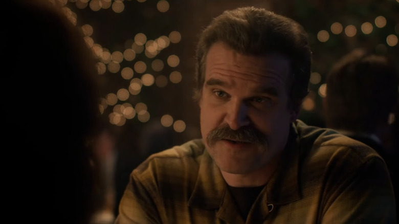 David Harbours Jim Hopper looks across frame against a blurry background in "Stranger Things"