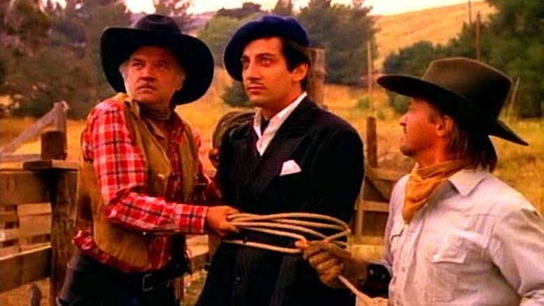 Two ranch hands holding the tied-up Pierre in The Cowboy and the Frenchman