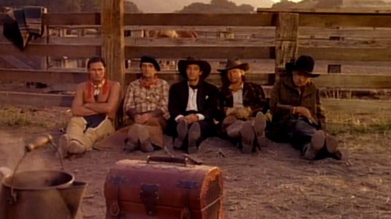 A line of Old West characters leaning against a fence in The Cowboy and the Frenchman