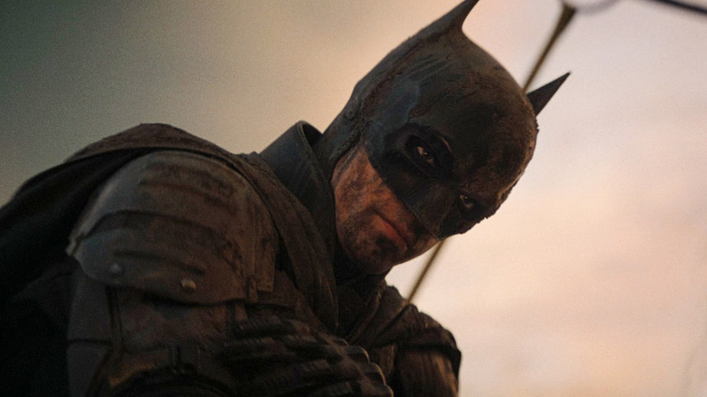 Batman (Robert Pattinson) crouches and looks down in The Batman (2022)