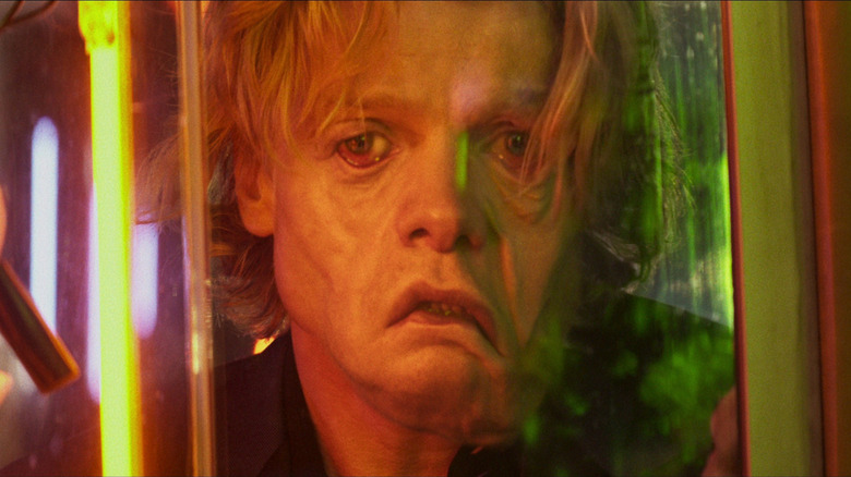 Tom Rhys Harries as Matt Hagen looking at a reflection of his face melting in Clayface