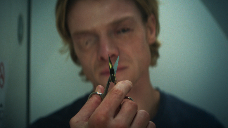 Matt Hagen looks at a pair of scissors in an airplane bathroom in Clayface