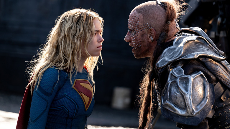 Milly Alcock as Supergirl wearing her superhero outfit and standing face-to-face with Matthias Schoenaerts as Krem in Supergirl