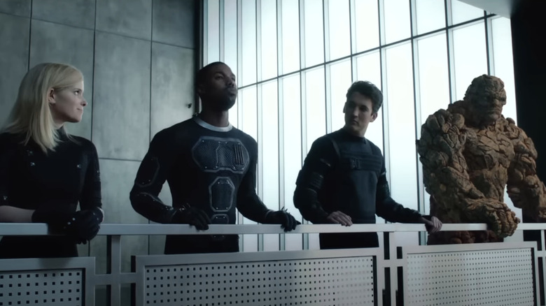 Miles Teller's Reed Richards, Kate Mara's Sue Storm, Michael B. Jordan's Johnny Storm, and Jamie Bell's Ben Grimm stand at a railing in Fantastic Four