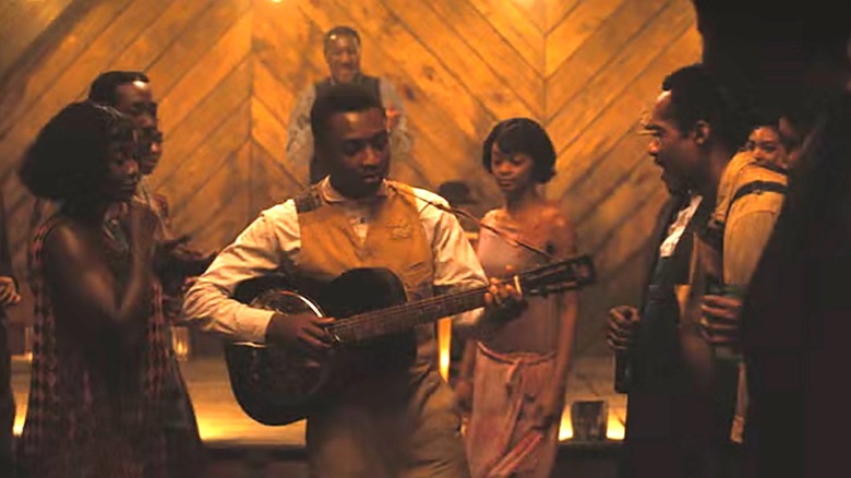 Miles Caton as Sammie playing the guitar for the juke joint in Sinners