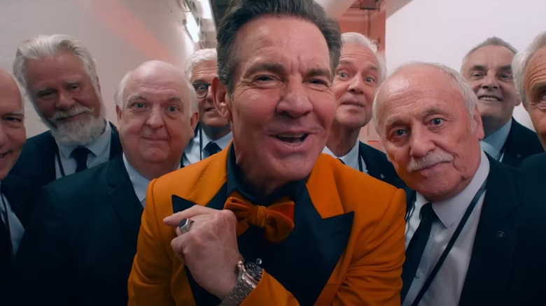 Dennis Quaid as Harvey in The Substance surrounded by a bunch of old men in suits