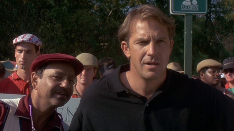 Roy (Kevin Costner) looks incredulous while standing at a crowded U.S. Open golf event, as Romeo (Cheech Marin) leans close to him in a scene from Tin Cup