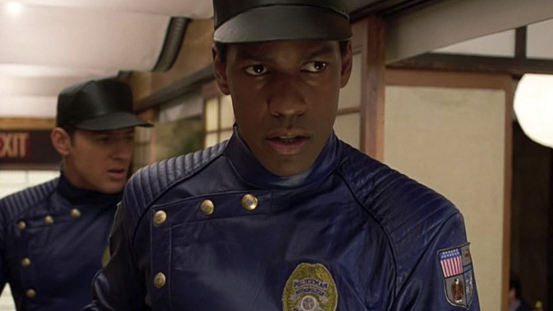 Denzel Washington's Lt. Parker Barnes wearing a uniform and walking through a corridor with another agent behind him in Virtuosity