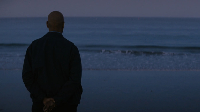 Robert McCall, que interpreta a Denzel Washington, está en la playa y mira al mar al amanecer en The Equalizer.