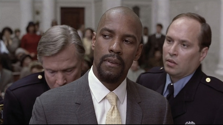Denzel Washington's Rubin Carter looks off to his right as two guards handcuff him in a court room in The Hurricane