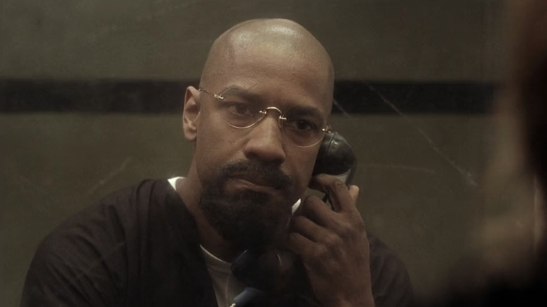 Denzel Washington's Rubin Carter talks on a phone as he sits behind a glass pane in prison The Hurricane