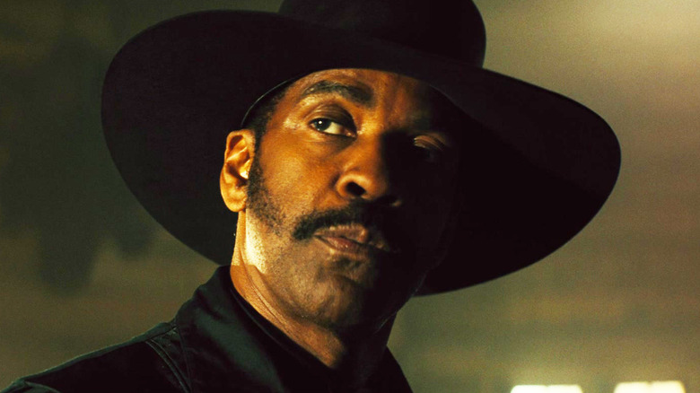 Denzel Washington's Sam Chisholm looks up while wearing a hat in The Magnificent Seven