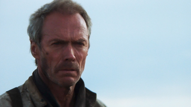 Clint Eastwood's William Munny stands against a blue sky in Unforgiven