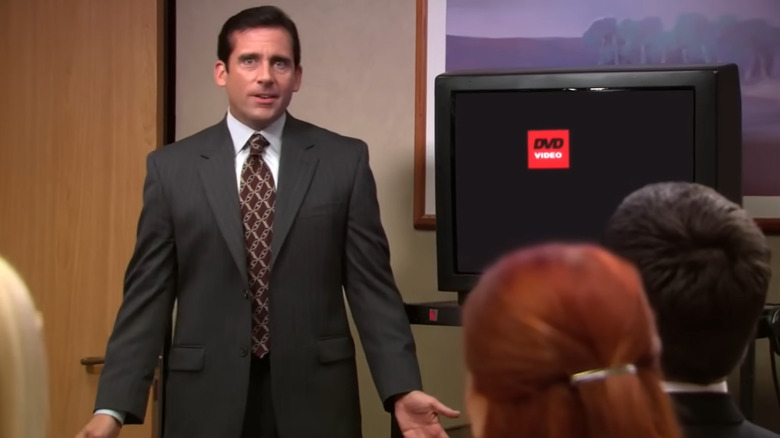 Michael Scott leading a meeting as the rest of the office watches the DVD screensaver menu in The Office episode Launch Party