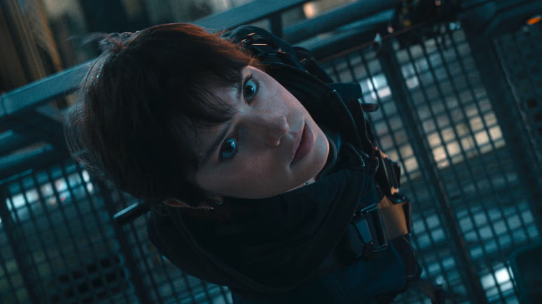 Joey (Daisy Ridley) looks up with a concerned expression while standing on a suspended scaffold and wearing tactical gear and a harness in Cleaner
