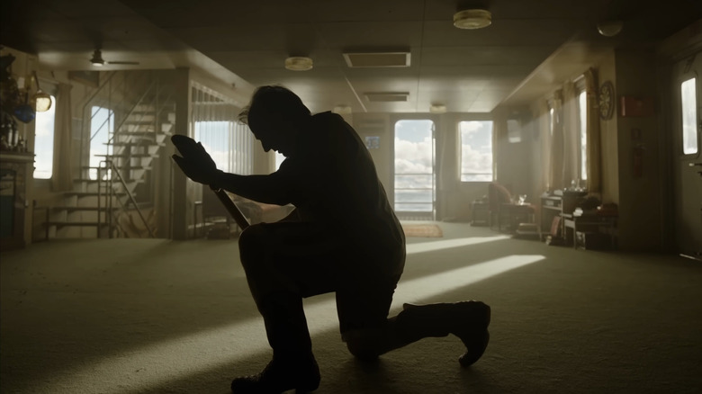 Tom Cruise as Digger Rockwell kneeling in a room with a shovel in Digger
