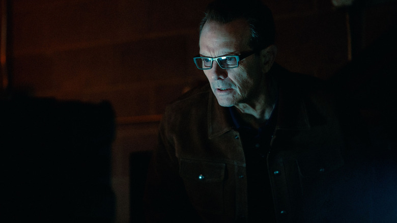 Baylor in a dark room with his face illuminated by a computer monitor in Onslaught