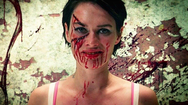 Lena Headey as a male standing in front of a wall covered in blood in Dredd