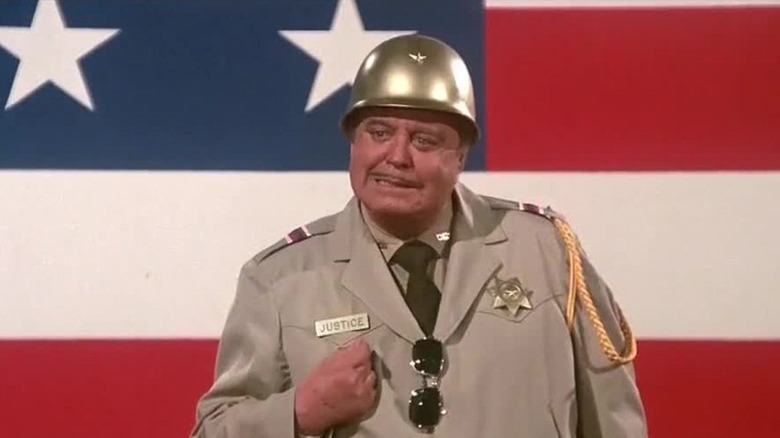 Jackie Gleason as Sheriff Buford T. Justice in front of a flag in Smokey and the Bandit Part 3