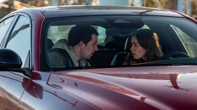 Josh O'Connor et Emily Blunt en tant que personnages anonymes assis dans une voiture rouge lors de la journée de divulgation